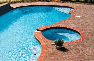 free form pool with built-in benches with tile details and a spa