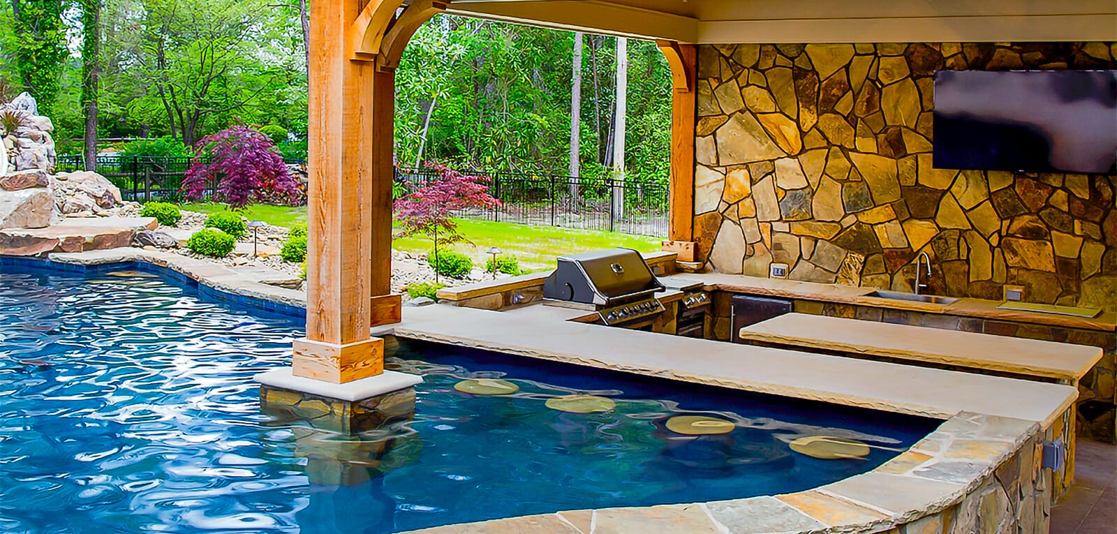 custom pool with swim up bar and outdoor kitchen