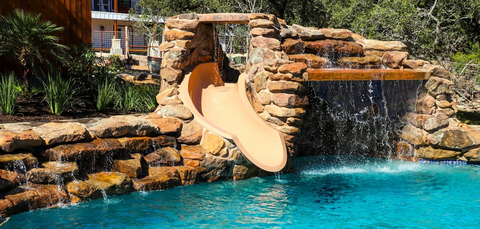inground pool with rock waterfall slide